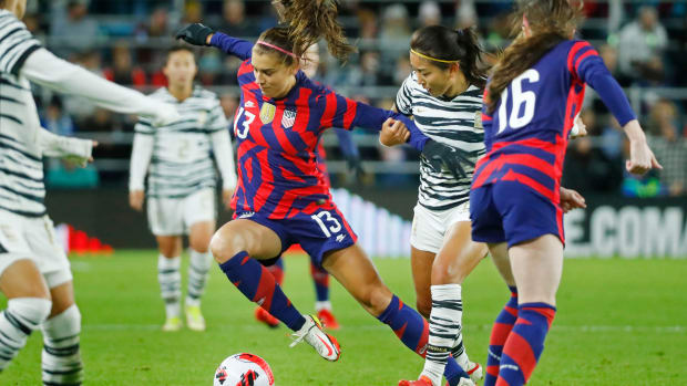 Alex Morgan goes to dribble the ball while a South Korea defender grabs her arm
